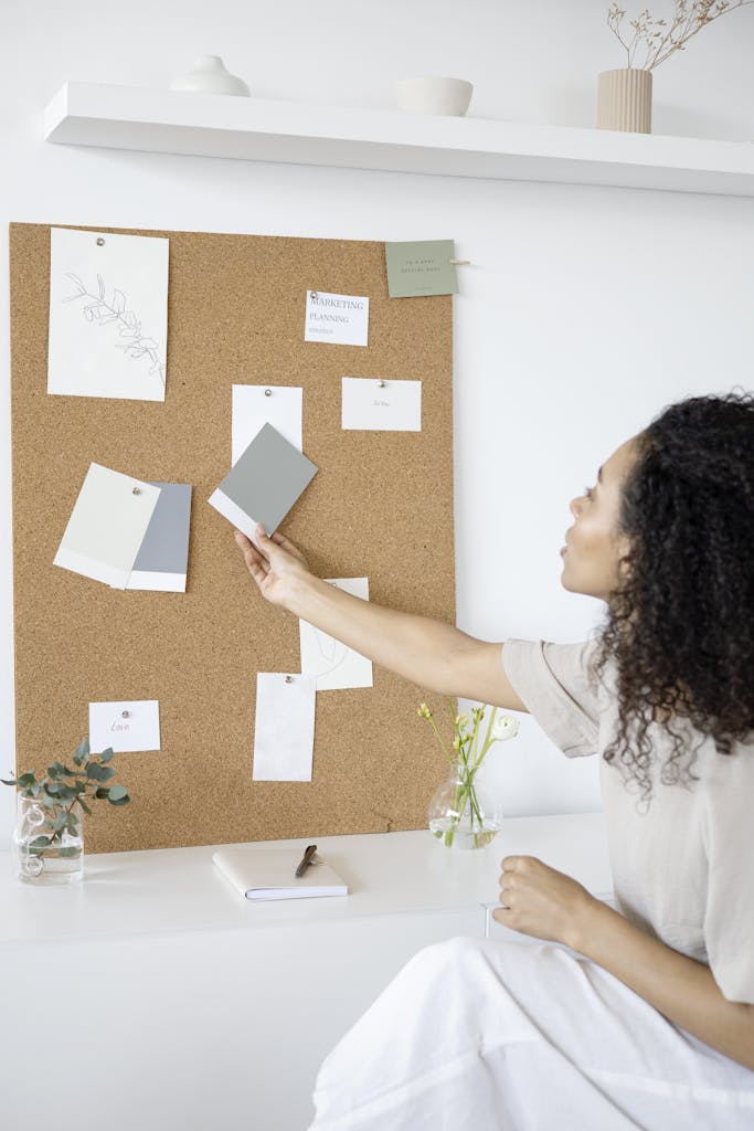 A woman curates a mood board in a minimalist home office setting, blending creativity and productivity.