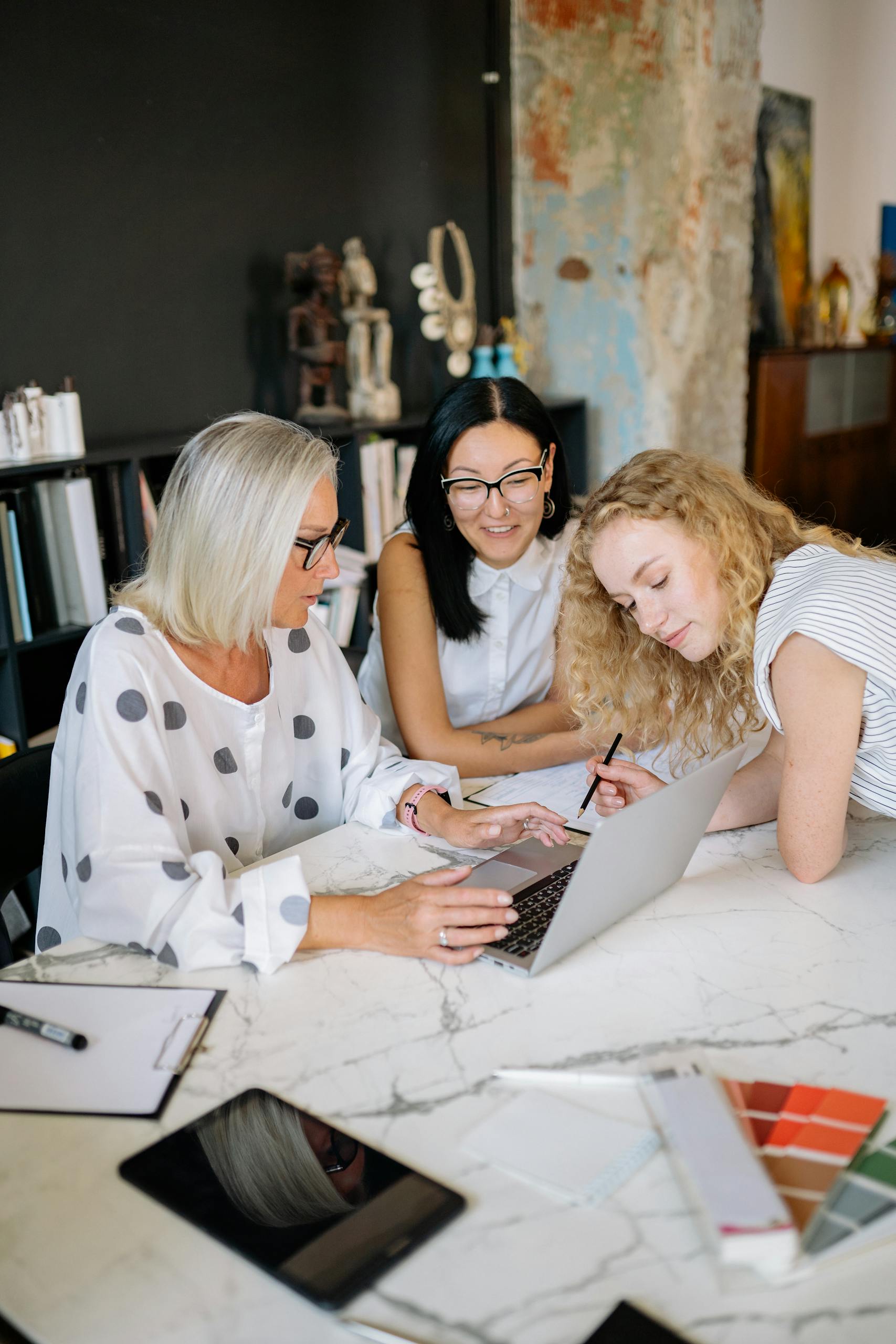 Group of women working together on a laptop in a stylish office, fostering teamwork.